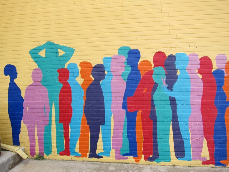 a colorful mural on the side of a building with people standing in front of it