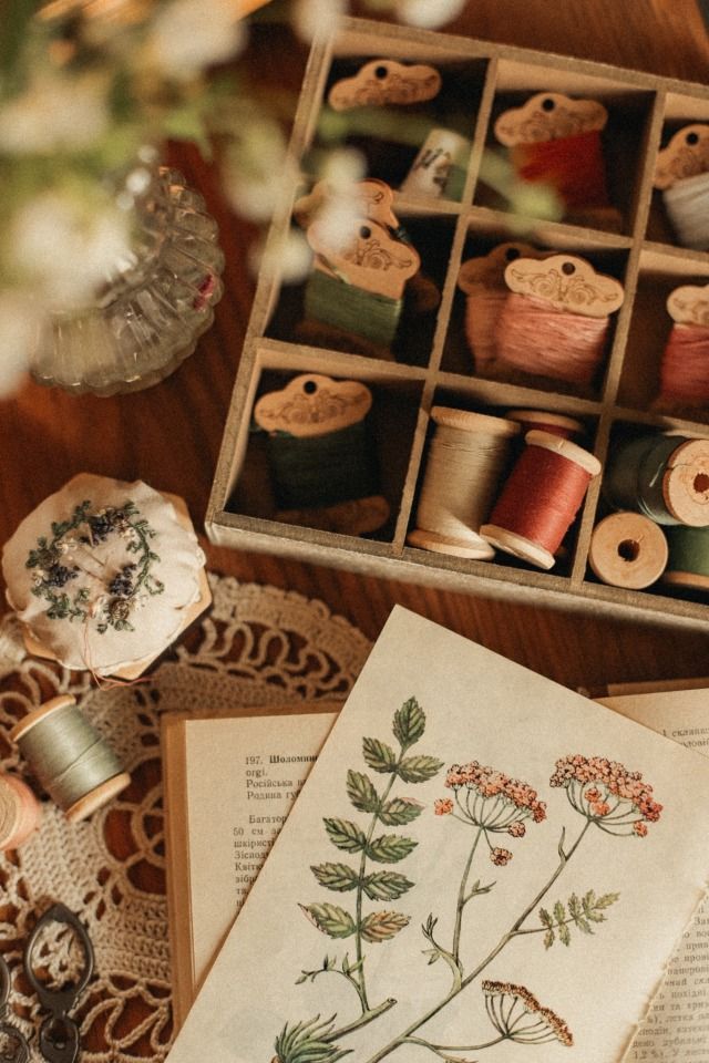 an open book sitting on top of a table next to spools of thread