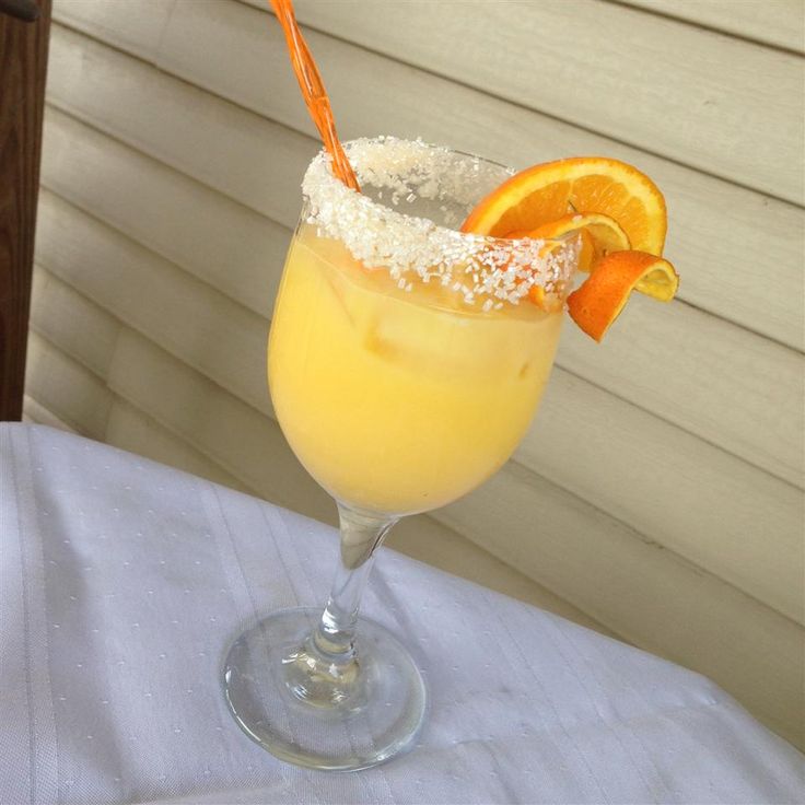 an orange drink with sugar and garnish in a glass on top of a table