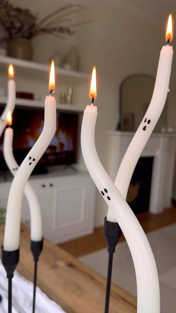 some candles are sitting in the middle of a room with a television on behind them