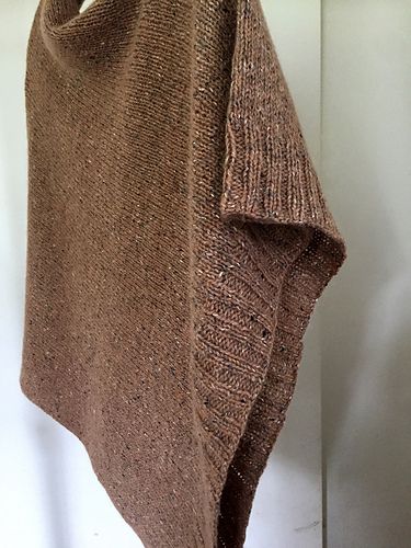 a brown sweater hanging up against a wall