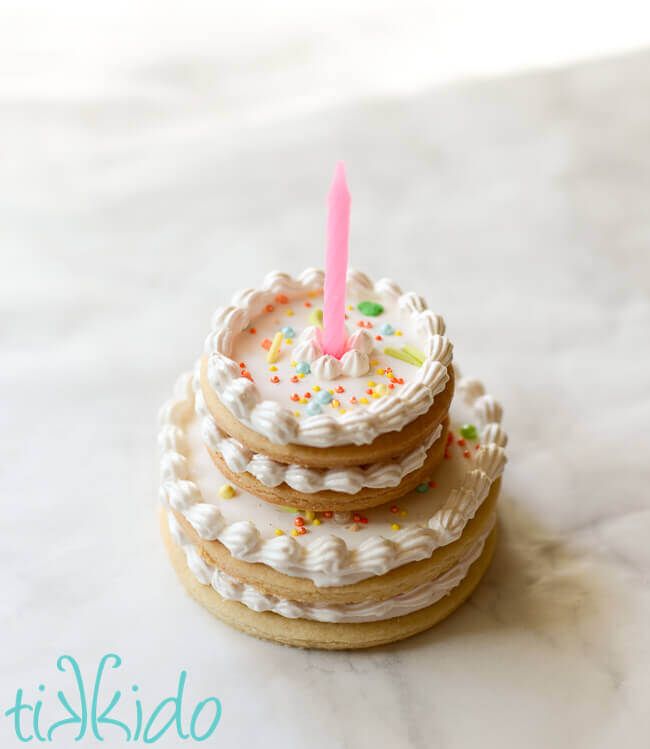 three cookies stacked on top of each other with a pink candle sticking out of one