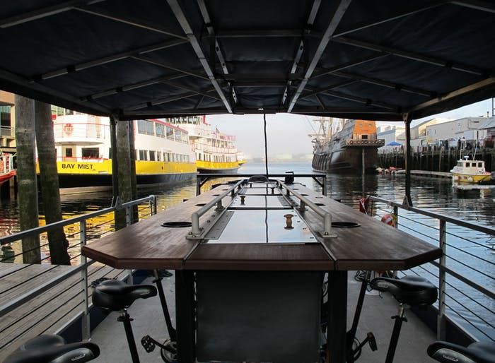 a long wooden table sitting on top of a boat dock next to a yellow and white ship