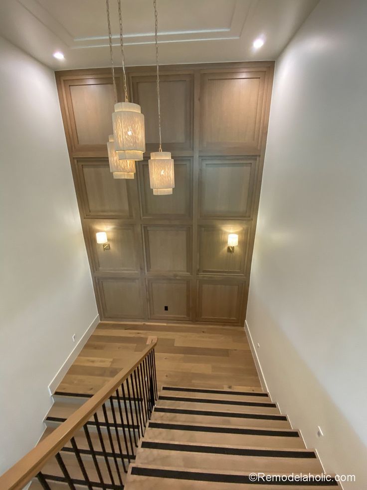 an empty staircase in a house with wooden floors and chandelier hanging from the ceiling