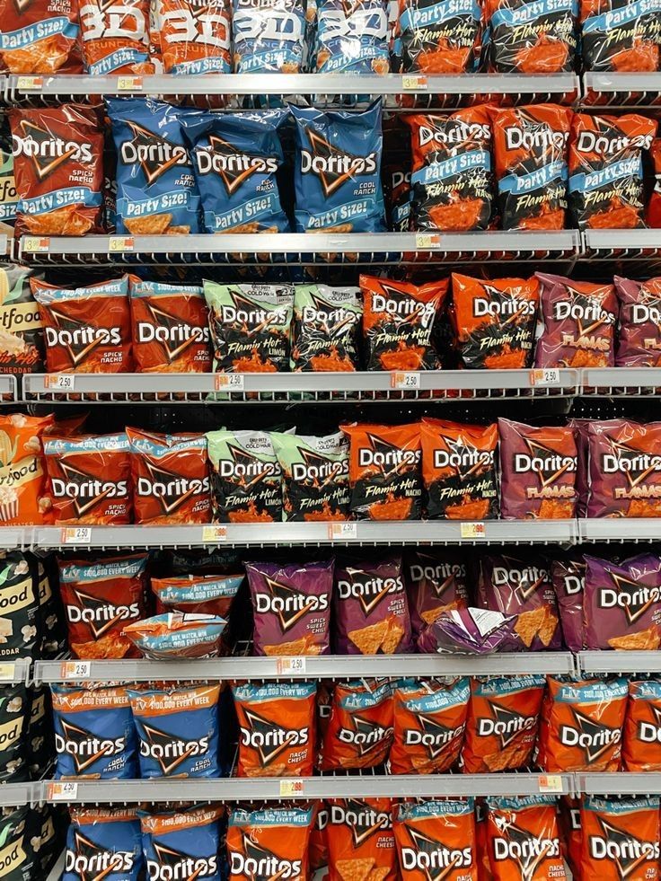 an assortment of donuts and chips on display in a grocery store, with the price tag down