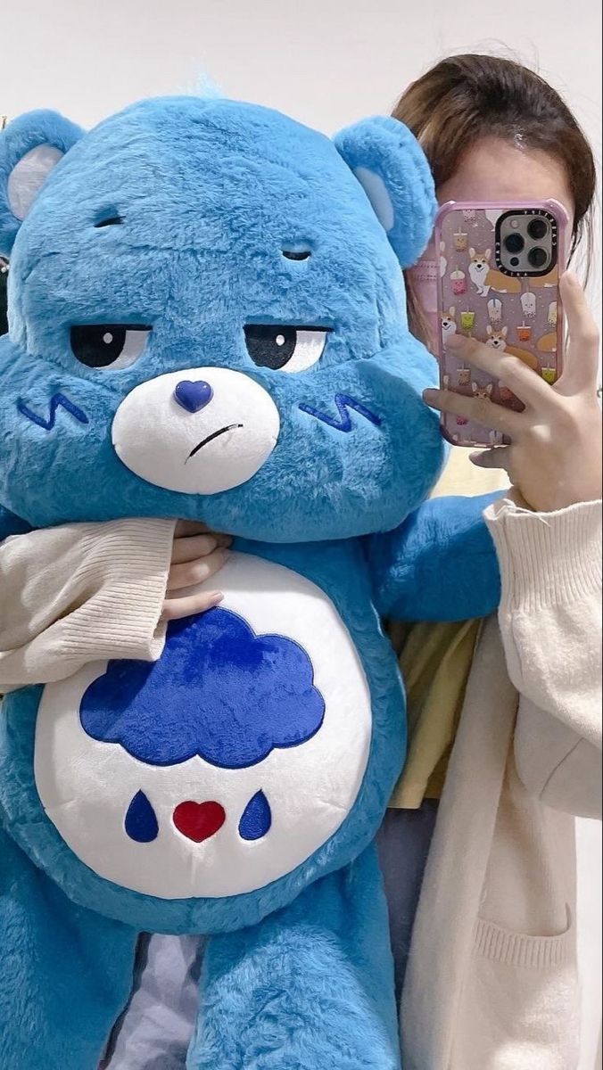 a woman taking a selfie with a large blue teddy bear holding a cell phone