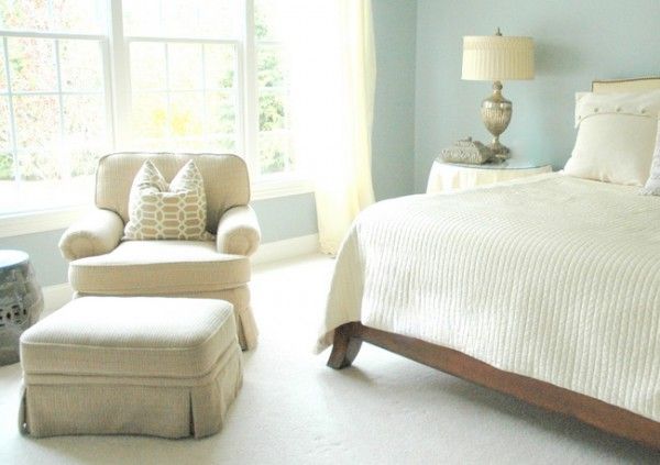 a bed room with a neatly made bed and a chair next to the window in front of it