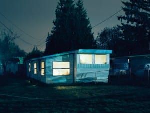 an old mobile home is lit up in the dark at night with its windows open