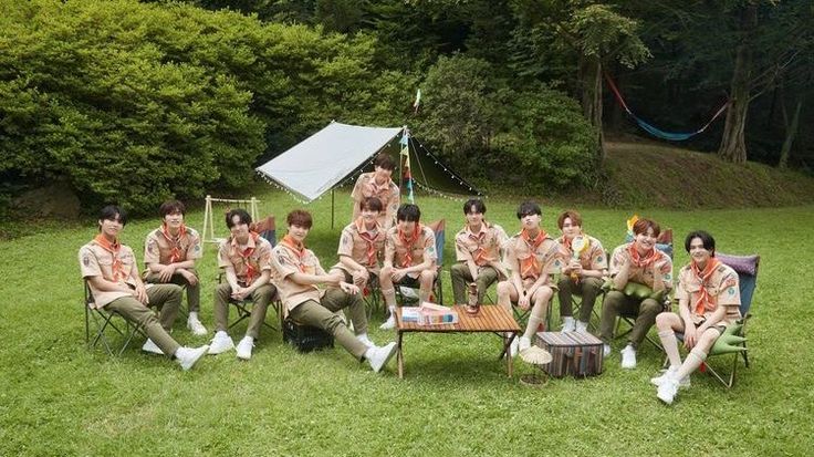 a group of young men sitting on top of a lush green field