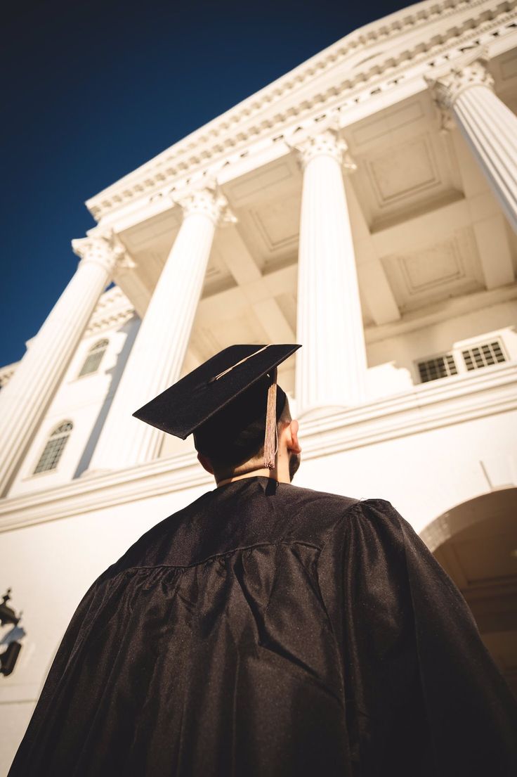 a man wearing a graduation cap and gown in front of a white building with columns