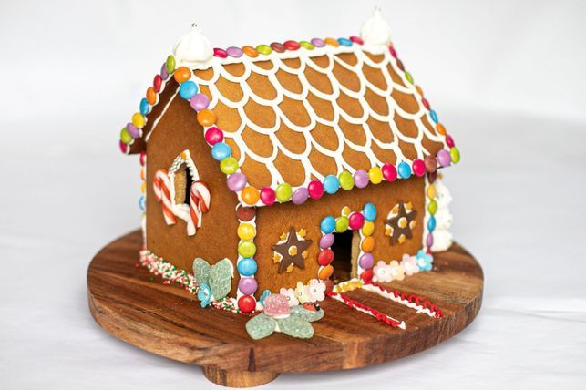 a gingerbread house is on a wooden stand