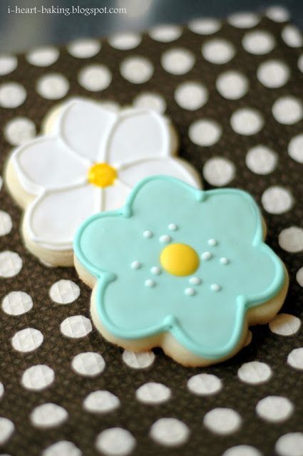 two decorated cookies sitting on top of a polka dot tablecloth with white and blue flowers