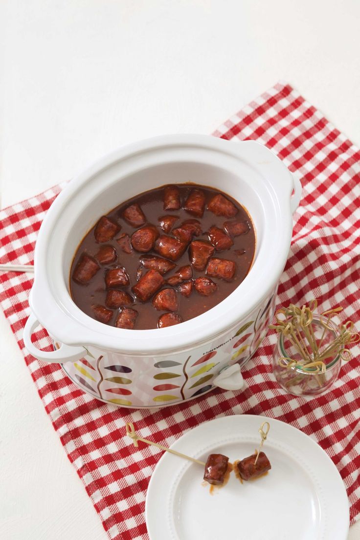 a bowl of stew on a red and white checkered table cloth next to a plate