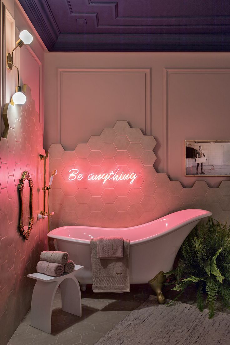 a bathroom with a pink bathtub and neon sign on the wall next to it