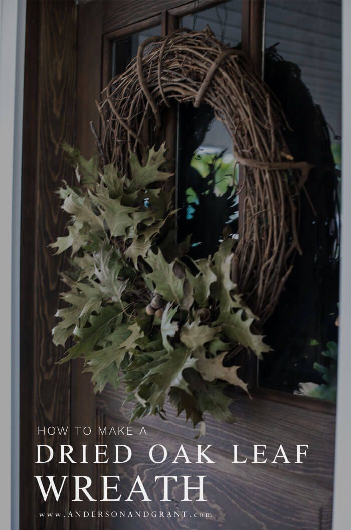 a wreath hanging on the front door of a house with green leaves and ivys