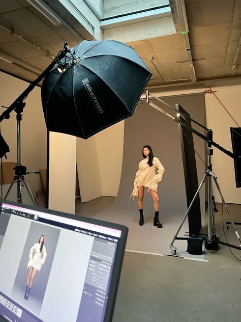 a woman is standing in front of a camera with an umbrella over her head and she is looking at the screen