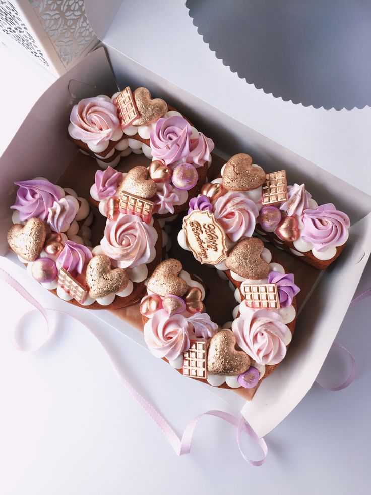 a box filled with lots of cupcakes covered in frosting and pink icing