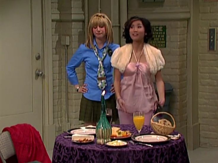 two women standing next to each other in front of a table with food on it