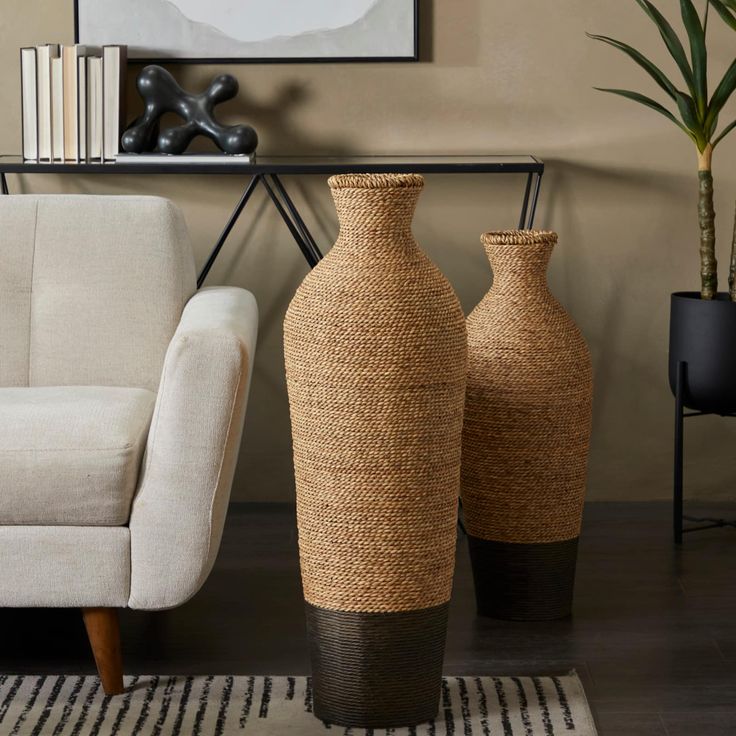 two large vases sitting next to each other on a rug in front of a couch