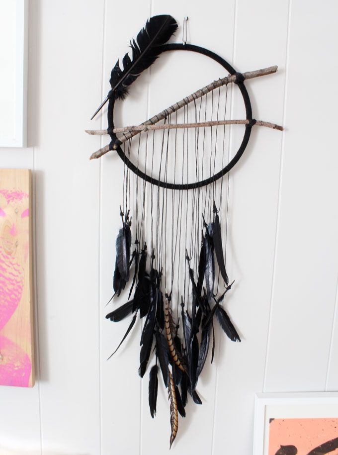 a black and white dream catcher hanging on a wall next to a pink painting with hearts