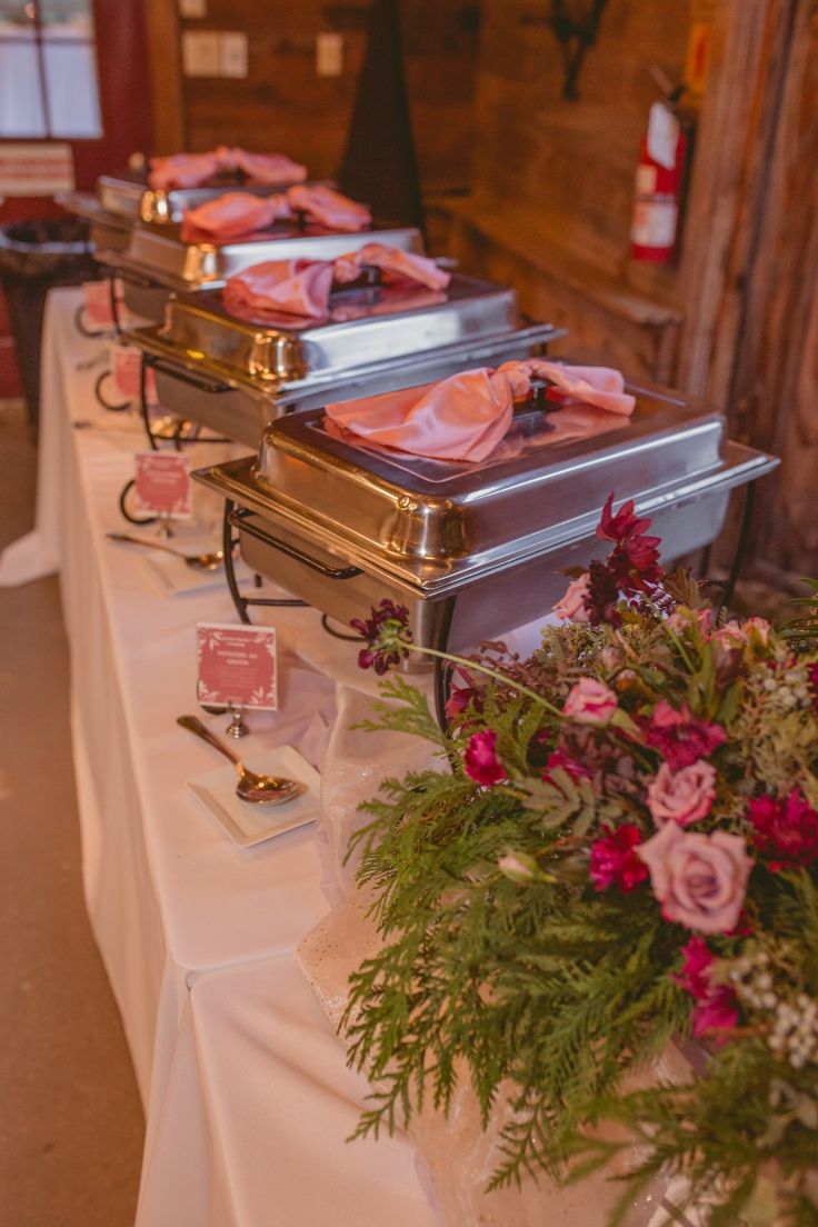 the buffet table is set up with silver trays and pink napkins on them