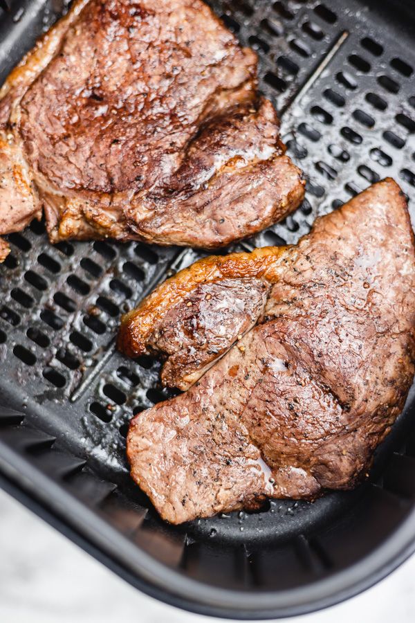 two steaks are being cooked on the grill