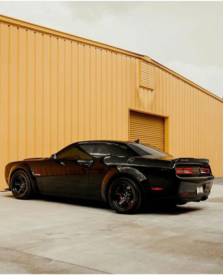 a black sports car parked in front of a yellow building