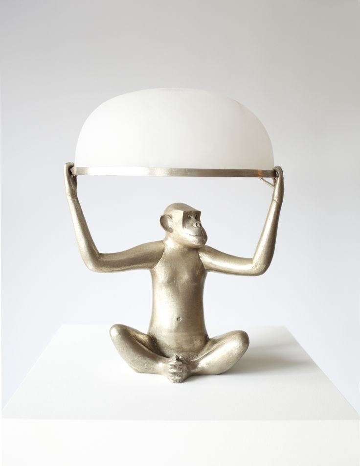 a silver statue holding a white lamp on top of it's head and legs