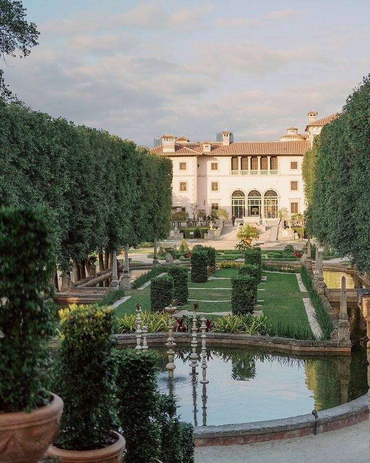 a large white building sitting next to a lush green park filled with lots of trees