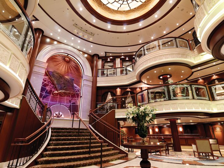 the inside of a cruise ship with stairs and chandelier