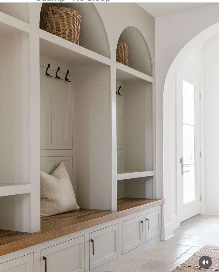 a room with some white cupboards and pillows on top of the shelves next to each other