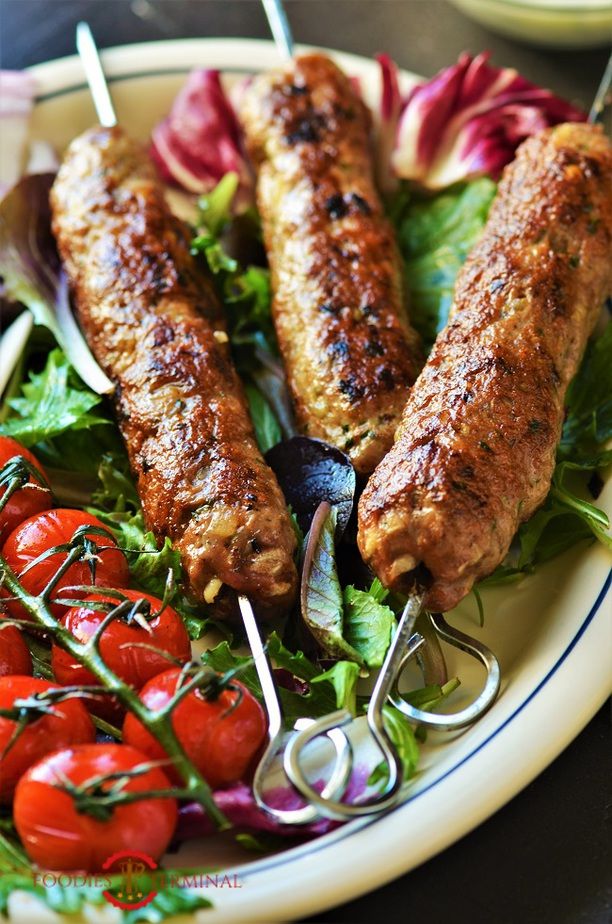 two sausages on skewers with tomatoes and lettuce in the foreground