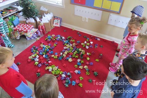 a group of children standing around a red rug covered in christmas decorations and confetti