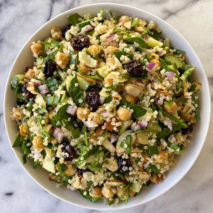 a white bowl filled with salad on top of a marble counter