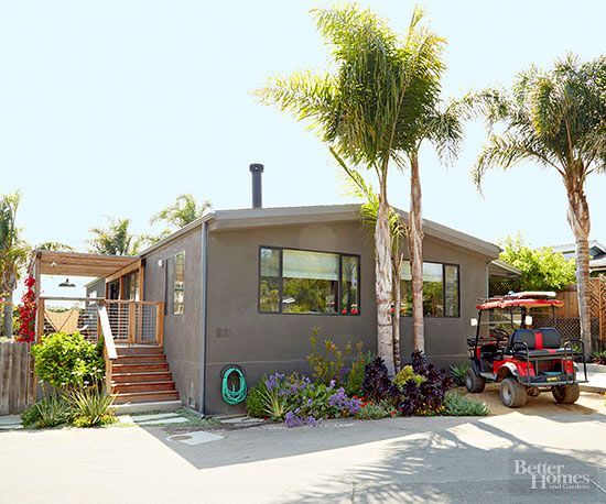 a small house with palm trees in front of it and a golf cart parked on the driveway