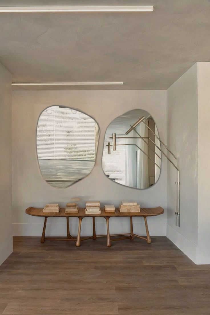 two circular mirrors hanging on the wall in a room with wooden benches and tables below them