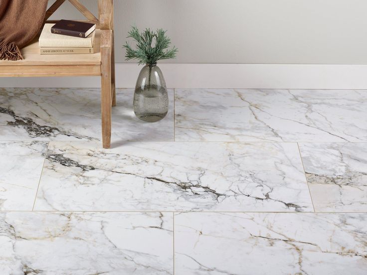 a white marble floor with a vase and book on the side table next to it