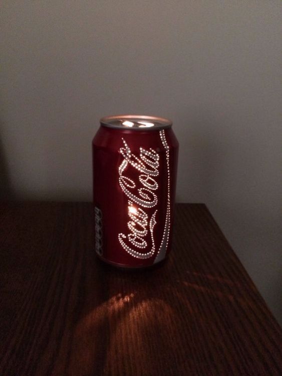 a coca - cola can sitting on top of a wooden table next to a wall