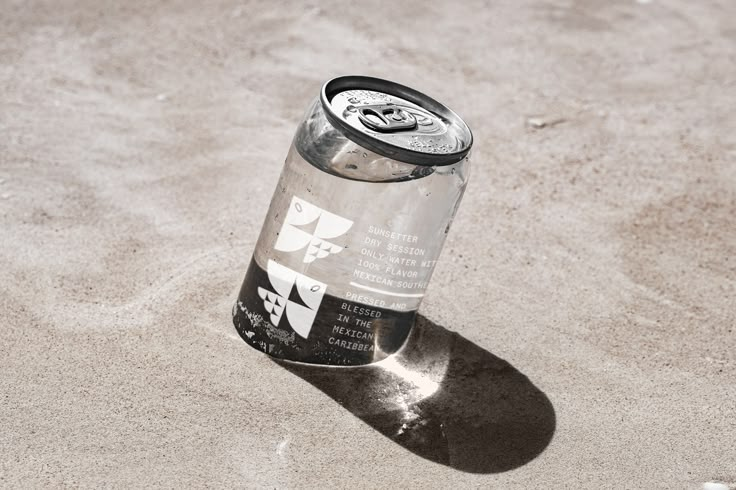 a can of soda sitting in the sand