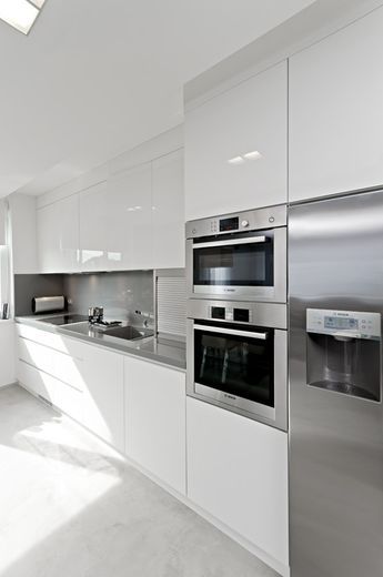 an image of a white kitchen with stainless steel appliance on the left side