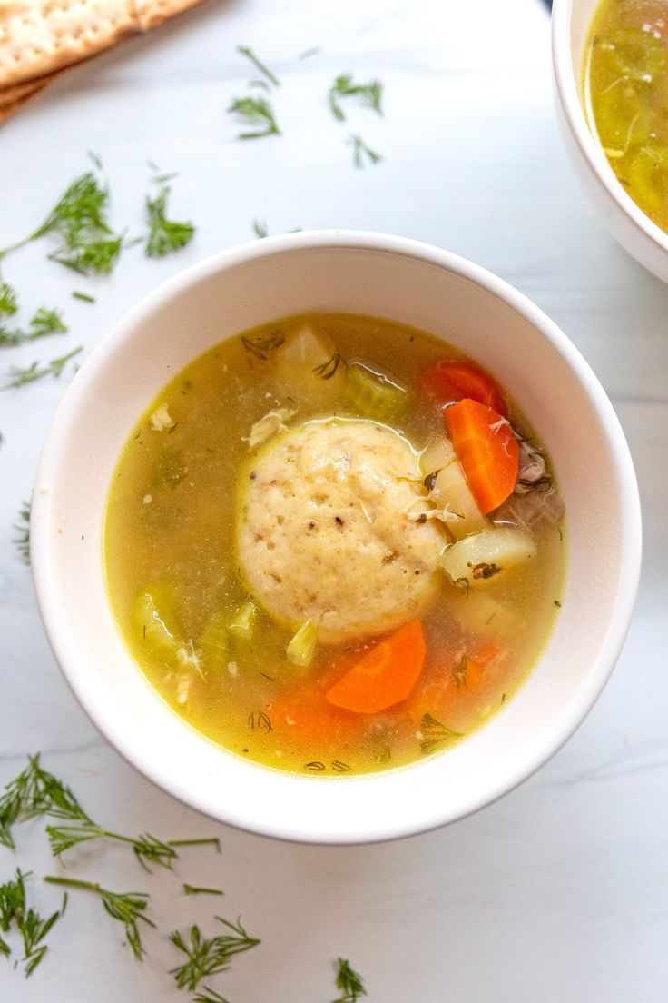 two bowls filled with soup and bread on top of a white countertop next to each other