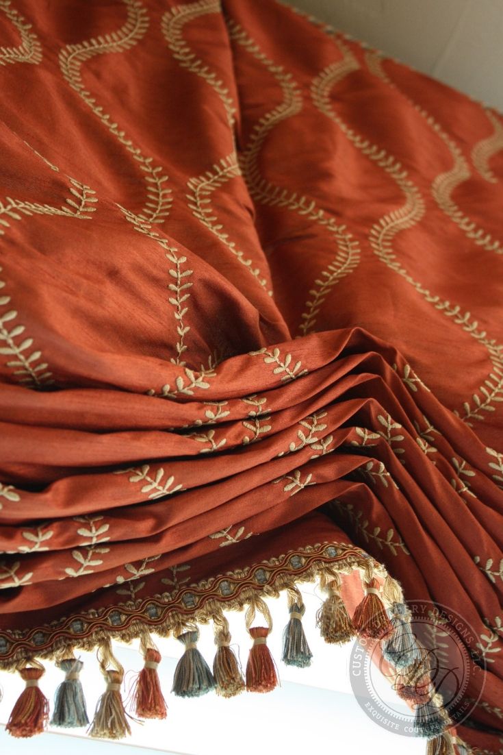 an orange and gold bed spread with tassels