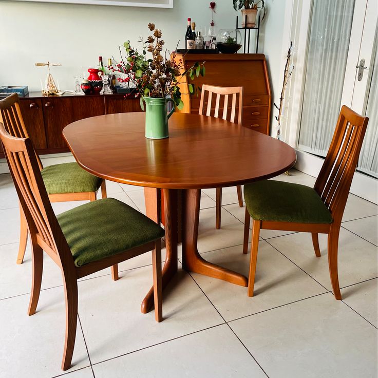 a wooden table with four chairs and a potted plant on top of the table