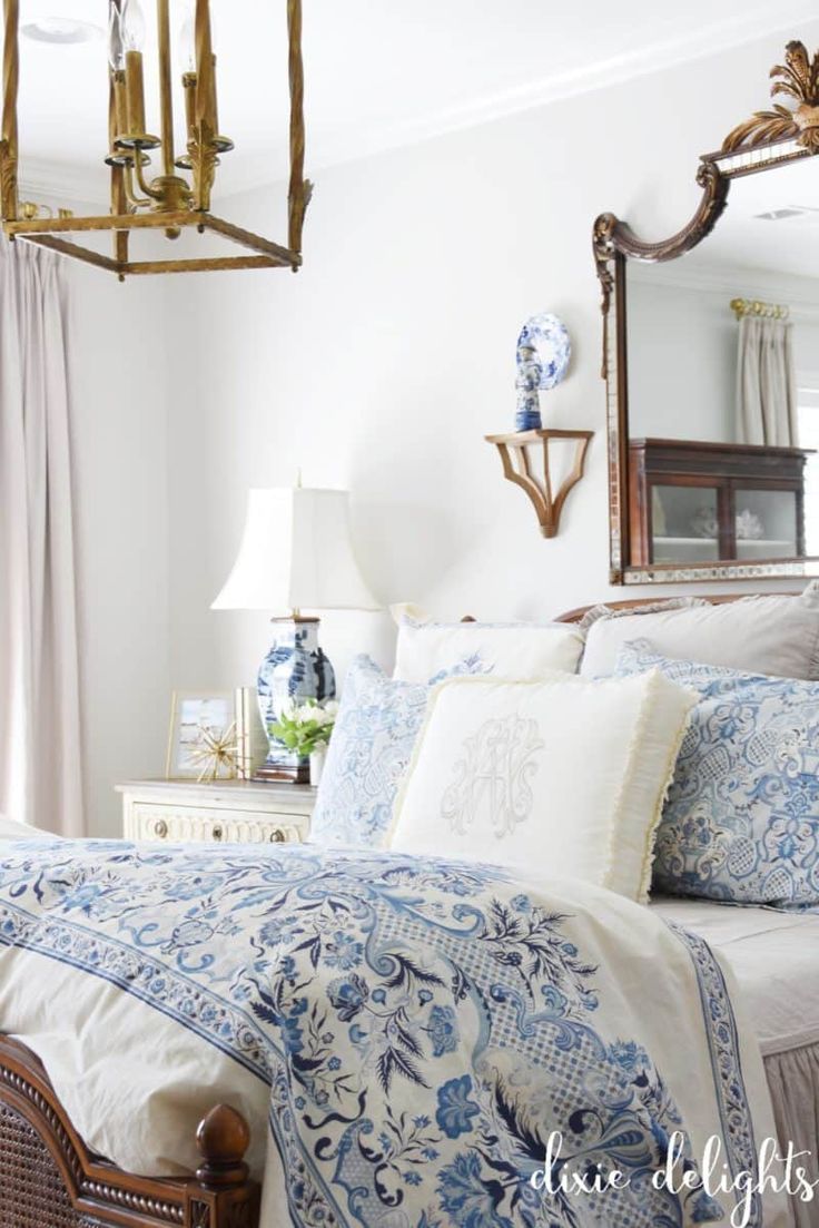 a bed with blue and white comforter in a bedroom next to a chandelier