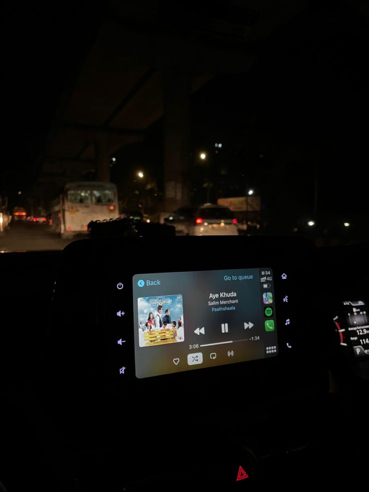 the dashboard of a car at night with cars in the background and lights from street lamps