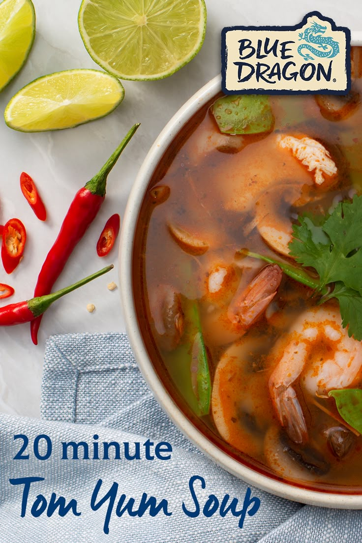 a bowl of soup with shrimp, cilantro and limes on the side