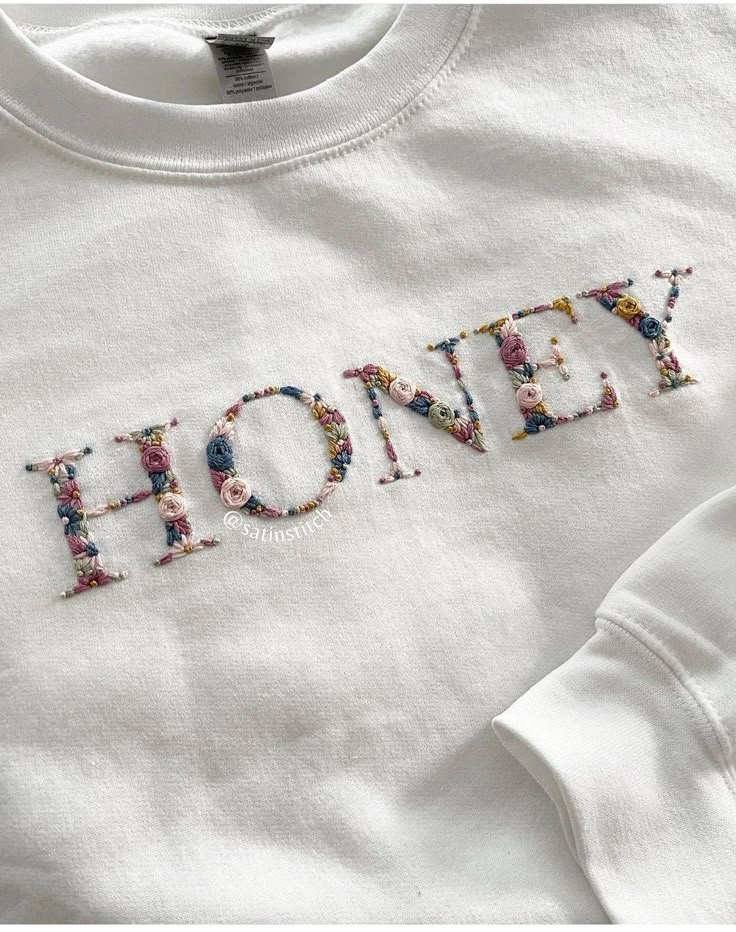 a white shirt with the word honey written in floral letters on it's chest