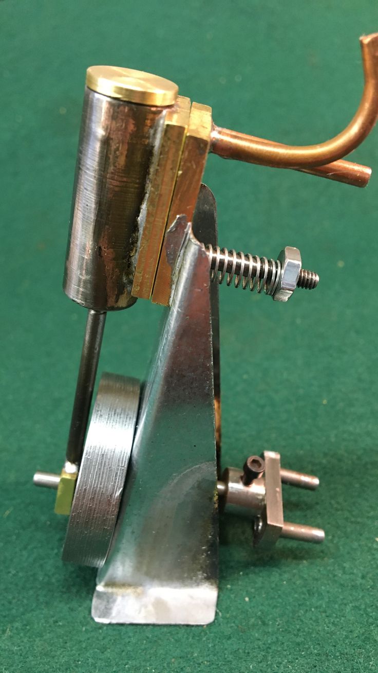 a small metal object on top of a green surface with a gold handle and two screws