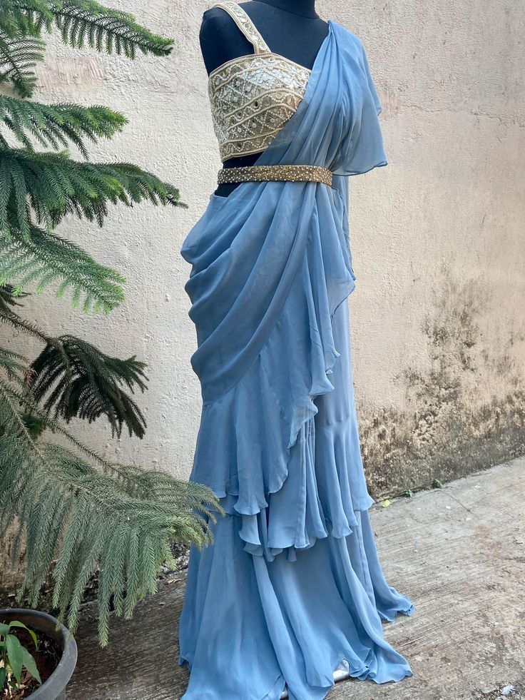 A two-piece blue ruffle saree set from the Priti Sahni collection. This beautiful blue georgette draped ruffle saree is paired with our classic mirror and pearl hand embroidered bustier blouse. The blouse has mirror-sequin tassels tie-up at the back. The outfit is completed with a heavy embroidered pearl belt.
Belt Included. Floor-length Ruffled Saree For Reception, Ruffled Pre-draped Saree For Diwali, Designer Semi-stitched Ruffled Blouse Piece, Pre-draped Georgette Lehenga For Designer Wear, Ruffled Georgette Saree With Traditional Drape, Ruffled Georgette Saree In Traditional Drape, Fitted Ruffle Saree For Reception, Fitted Ruffled Saree For Reception, Designer Wear Saree With Ruffles In Traditional Drape