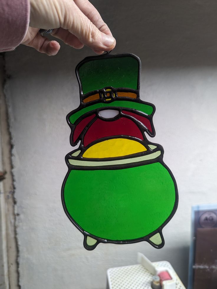 a hand holding up a sticker with a green hat and lepreite on it